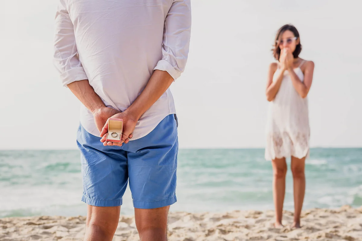 Man holding box with marriage ring making propose to his girlfriend at the beach