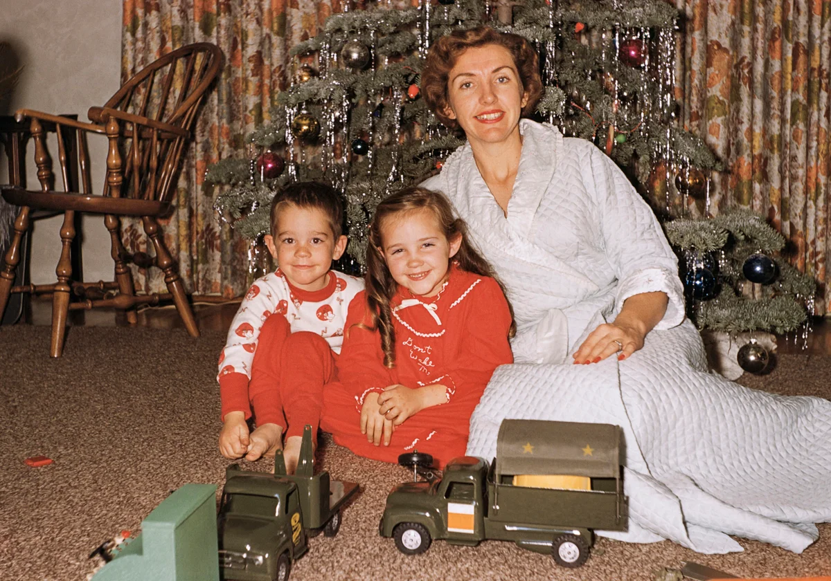 Retro photo of mother posing with son and daughter near Christmas tree