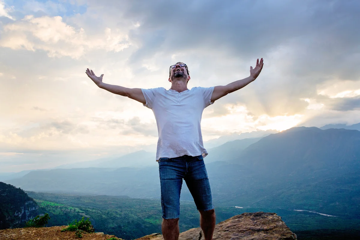 A happy man with has arms stretched out and looking up at the sky