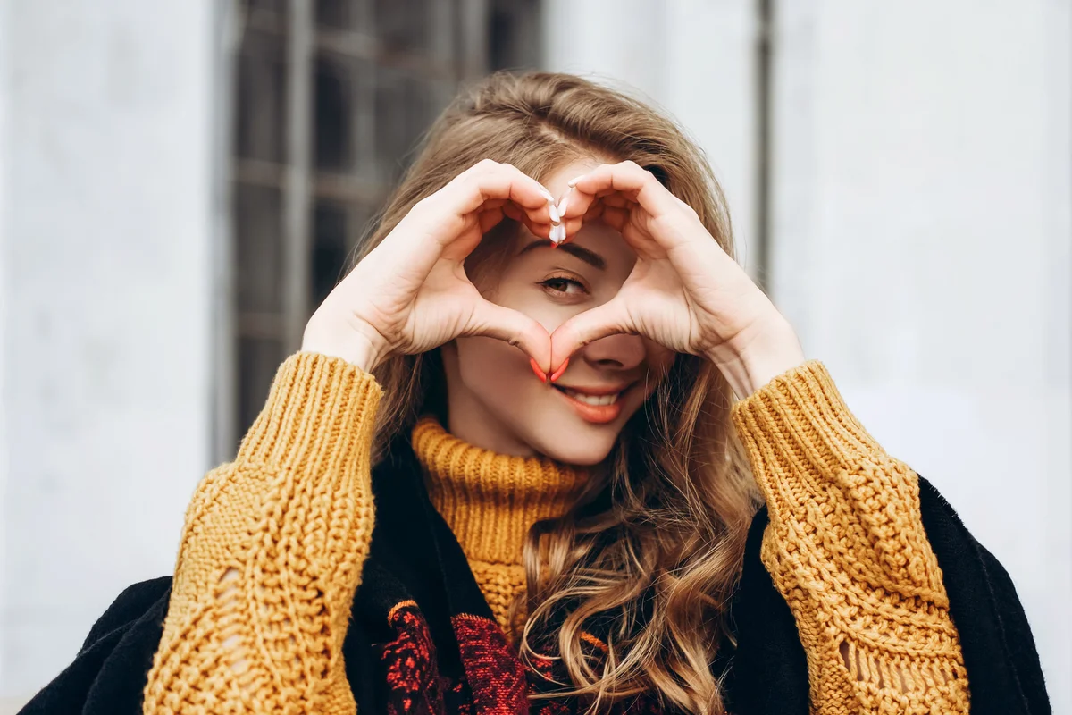 Young woman showing heart shape around her eye