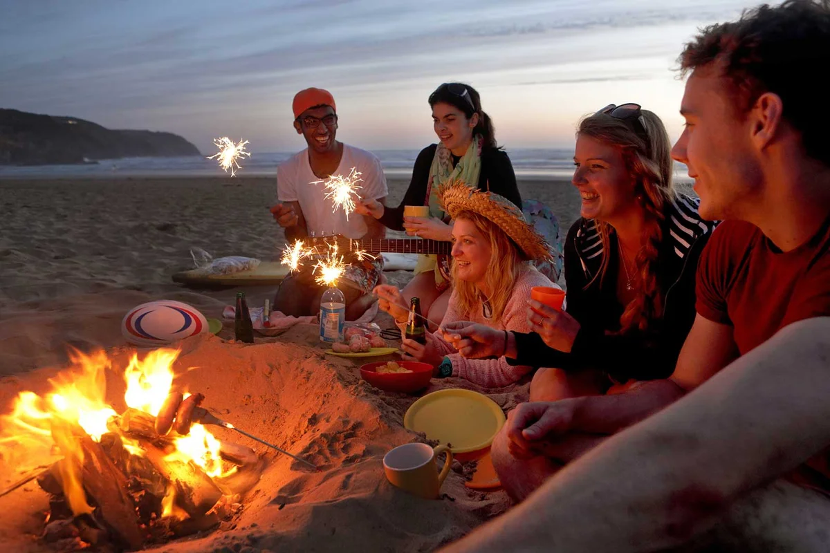 friends lighting sparklers at campfire on beach