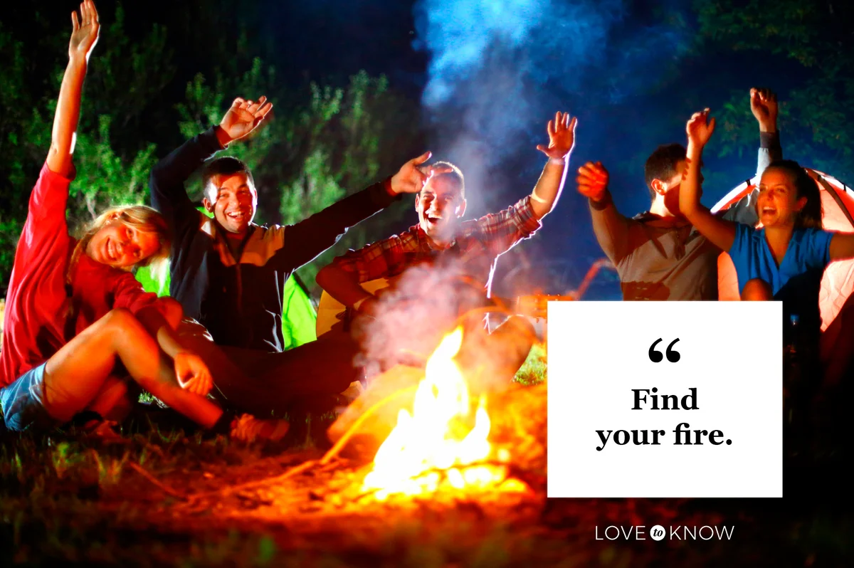 friends celebrating hands up around campfire