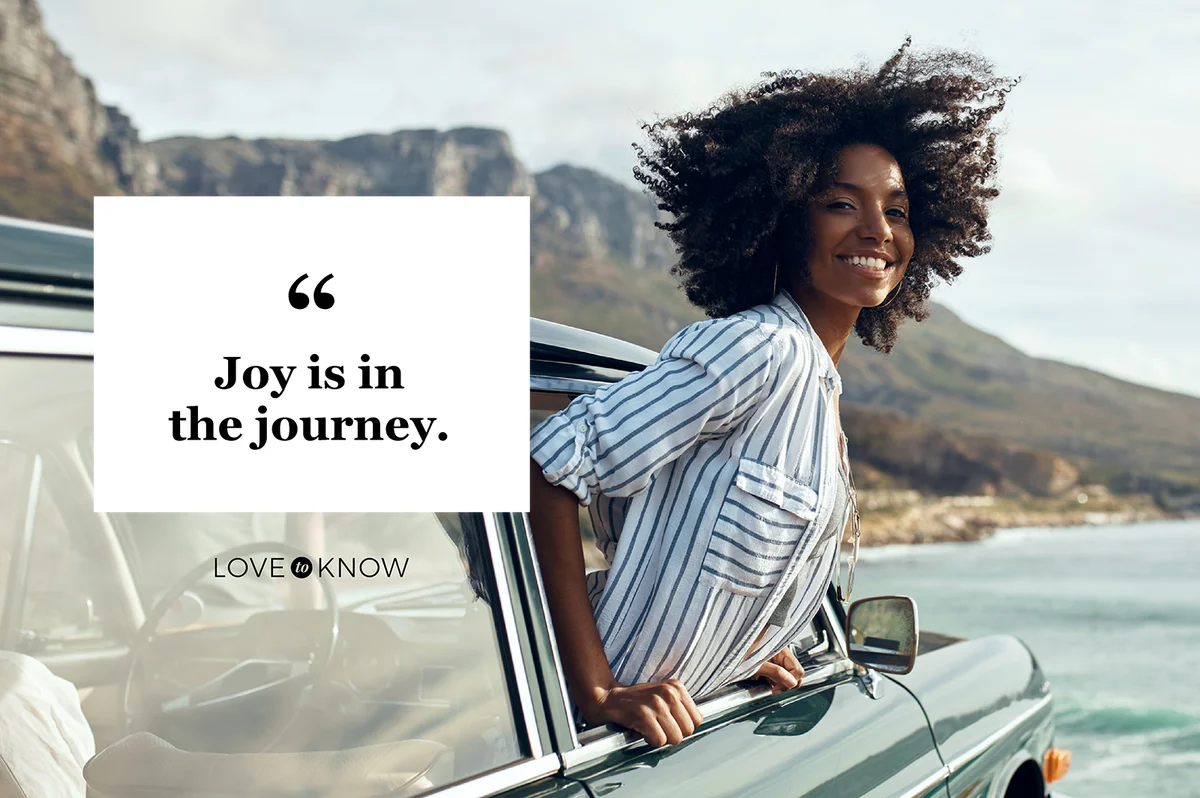 Happy young woman leaning out of a car window on a road trip