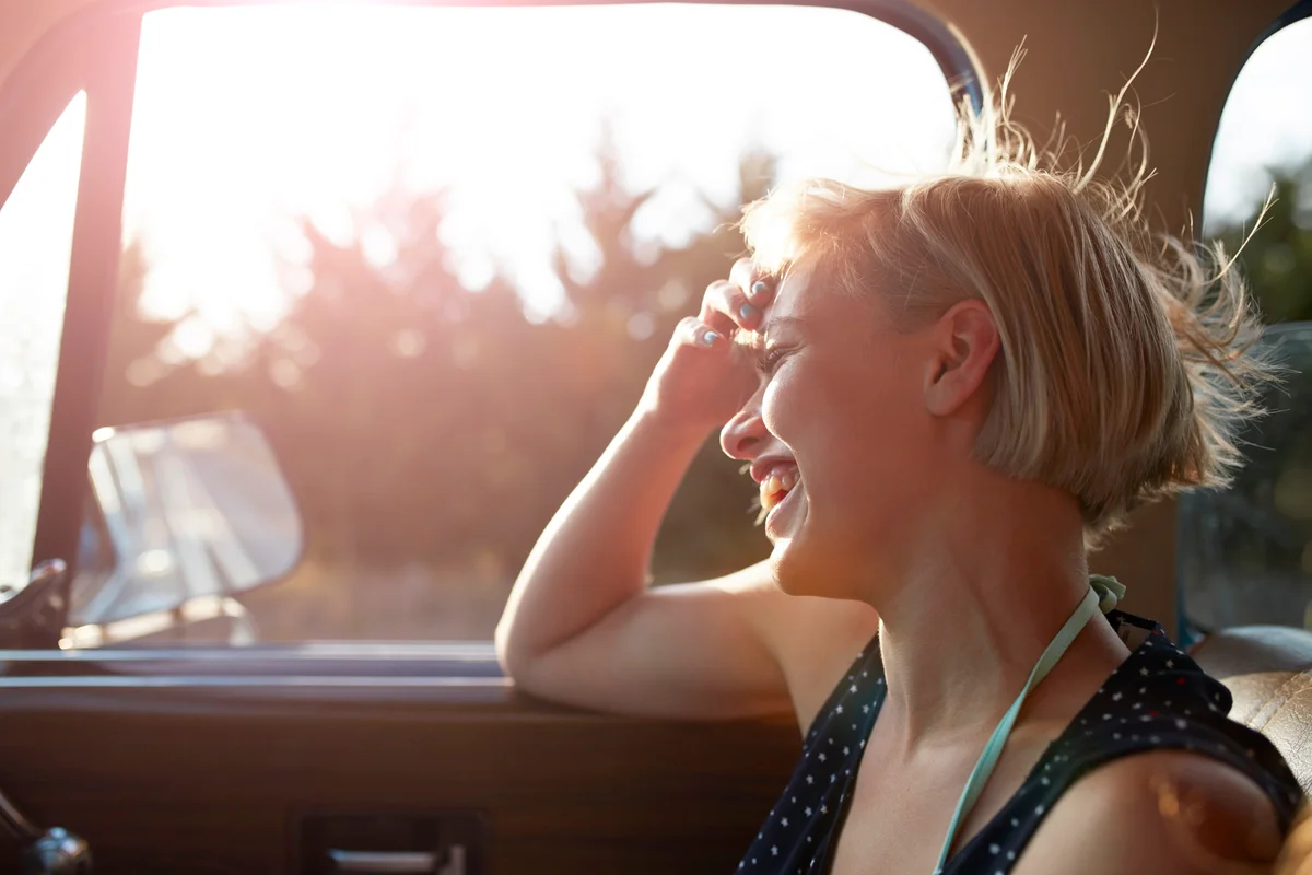 Woman laughing in car with open window