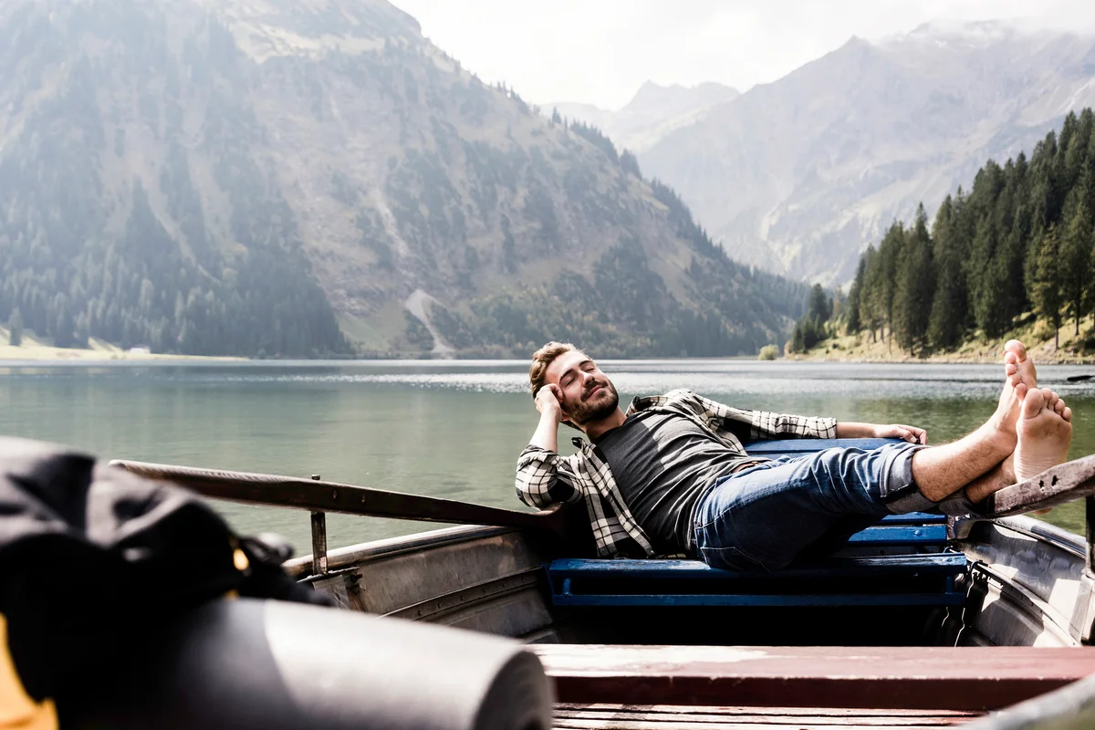 Relaxed man in boat on mountain lake