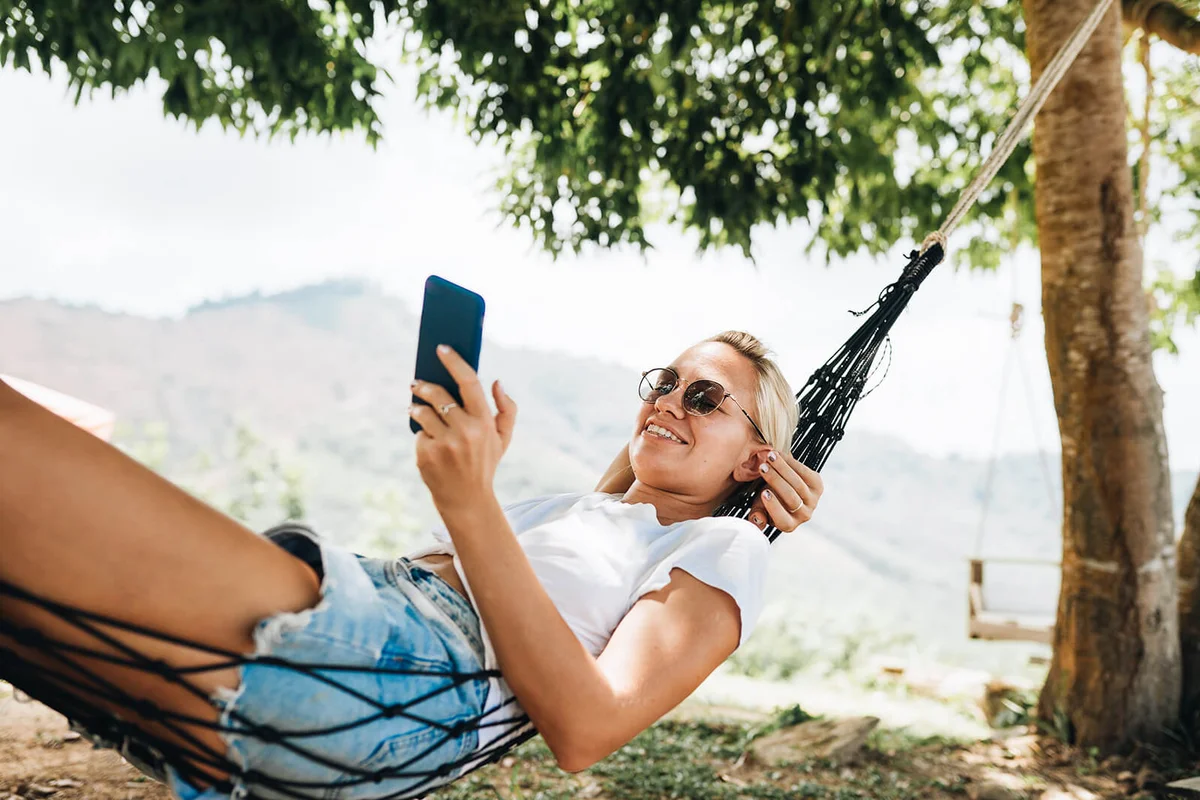 Woman lying in hammock and using mobile phone