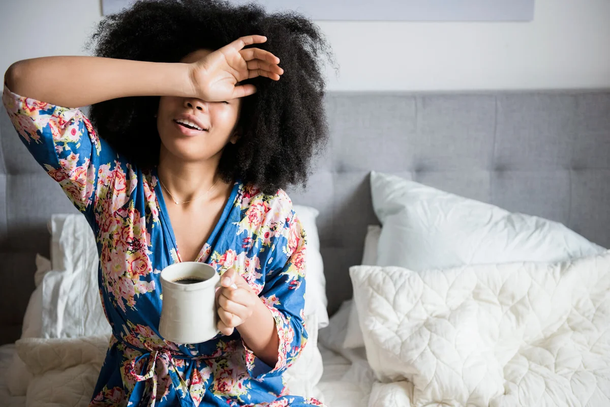 woman sitting in bed drinking coffee