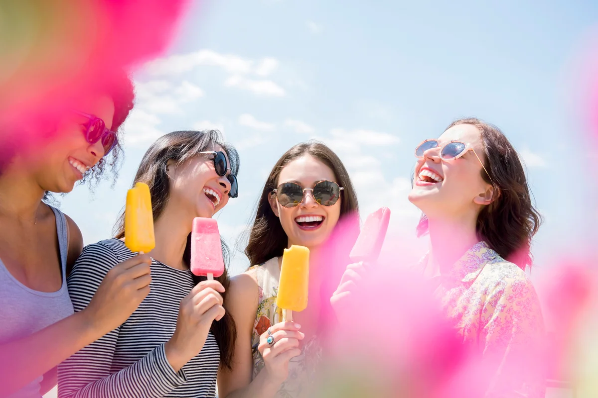 Happy women eating flavored ice-cream outdoors