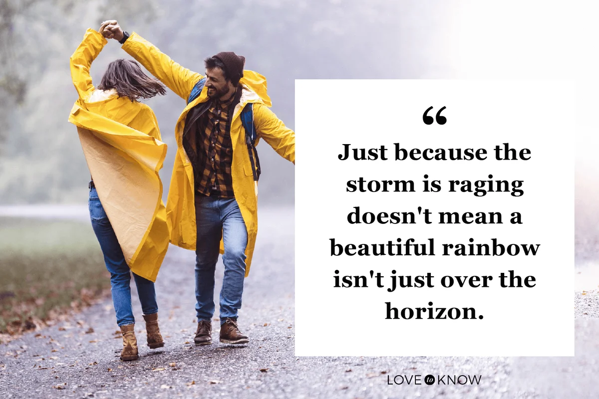 Happy couple in raincoats having fun while dancing on a rain in misty forest