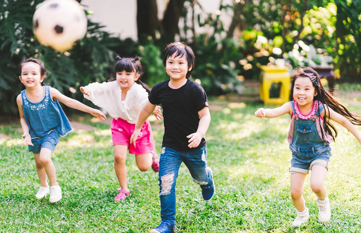 Children Running On Grassy Field In Park
