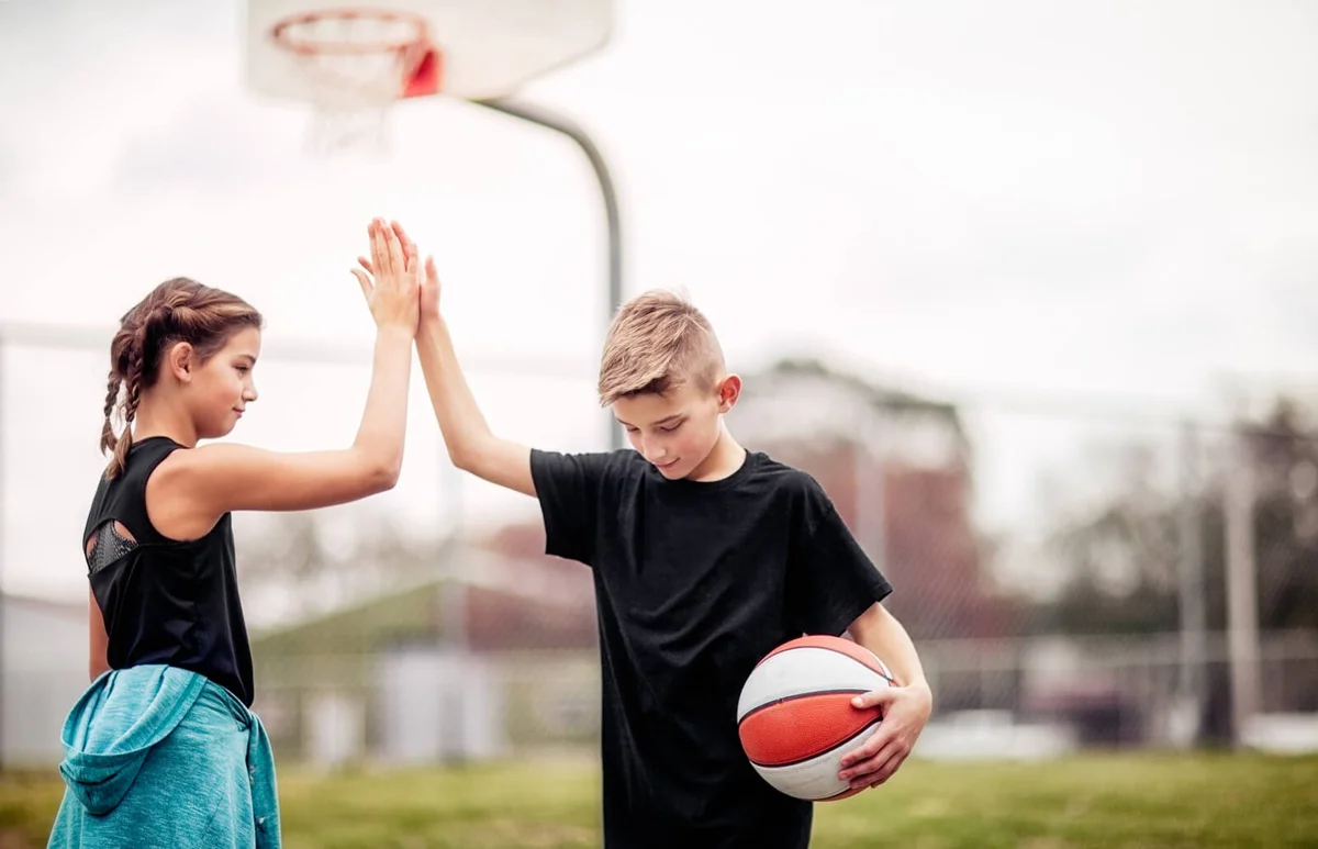 boy and girl giving each other a high-five after basketball game