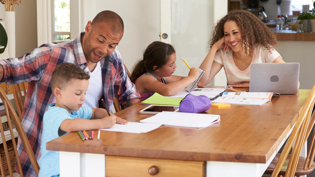 Parents Helping Children With Homework At Table
