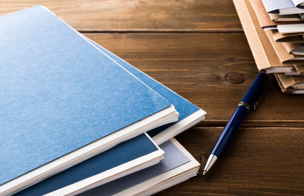 Writing instrument and stack of papers paperwork on office desk table