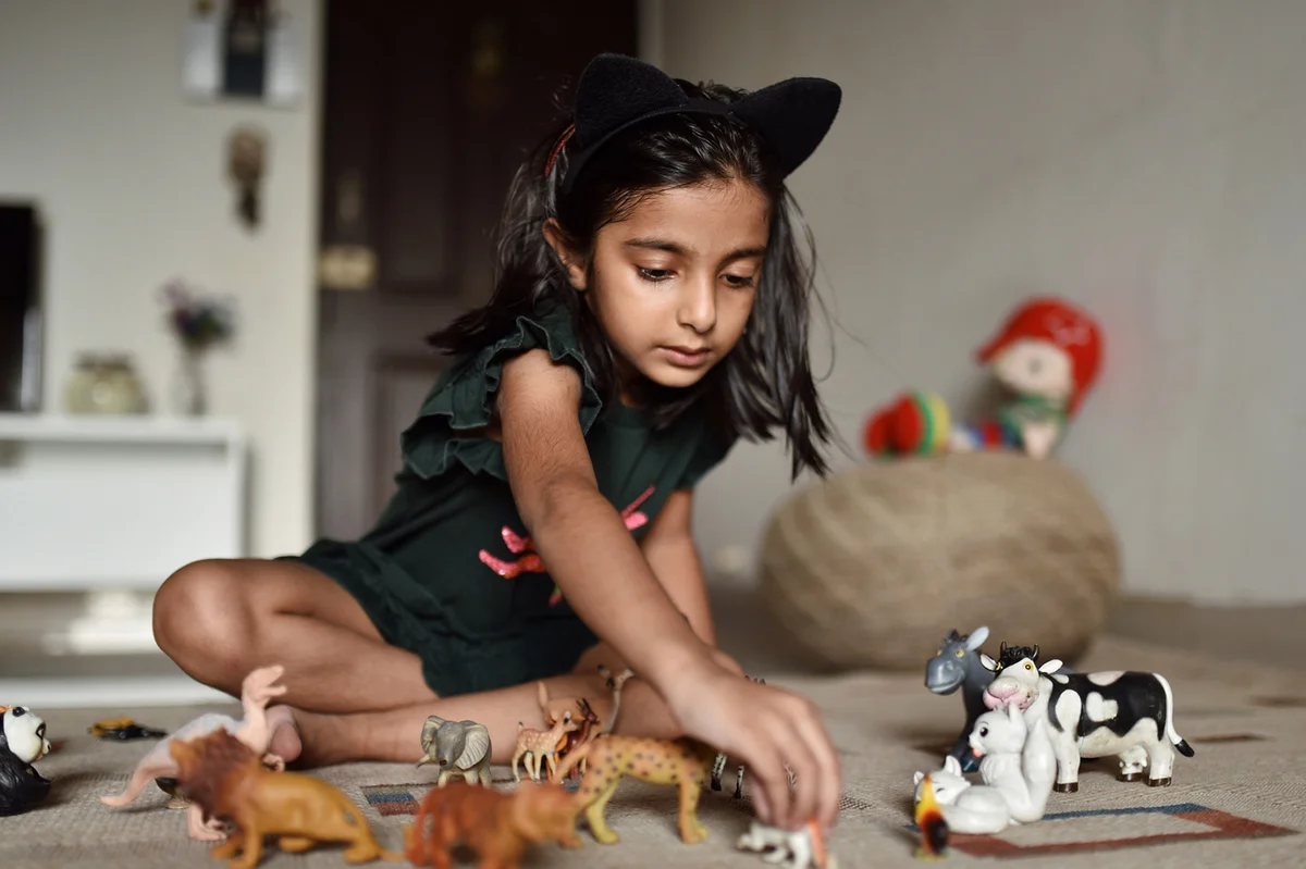 Girl lining up animal toys