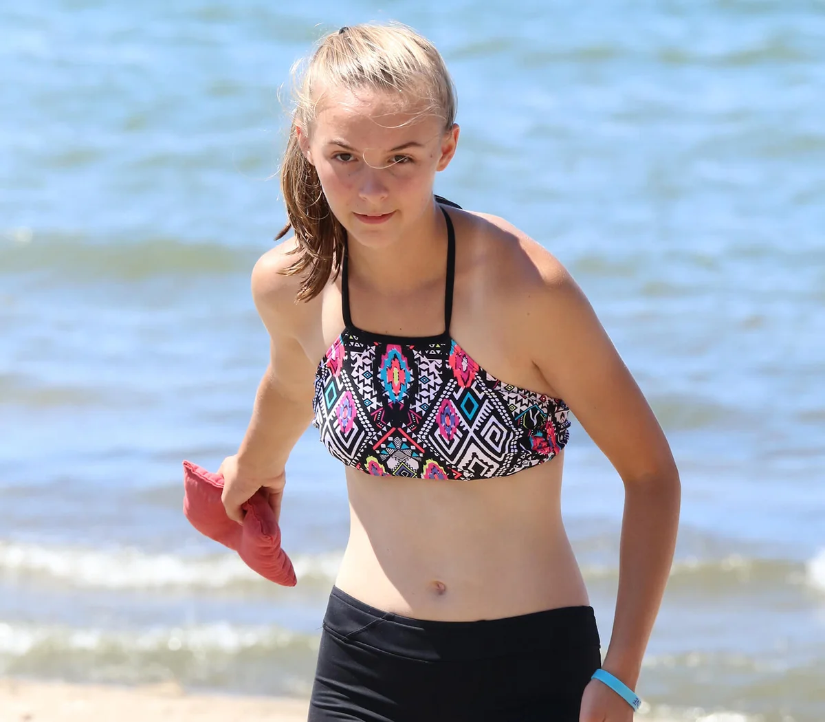 Young girl on the beach tosses a bean bag during a corn hole game