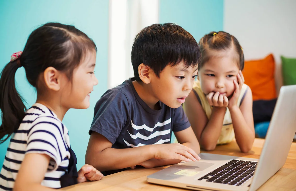 Three children using a laptop