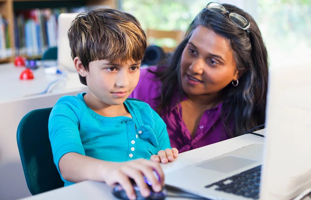 Teacher helping student using laptop