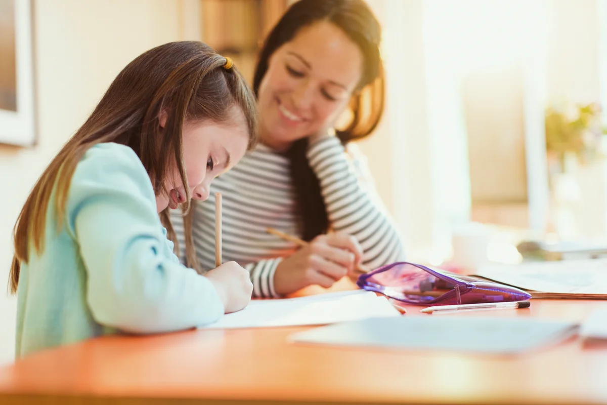 Mother watching daughter do homework