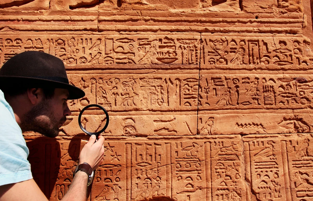 Archeologist reading hieroglyphics with magnifying glass