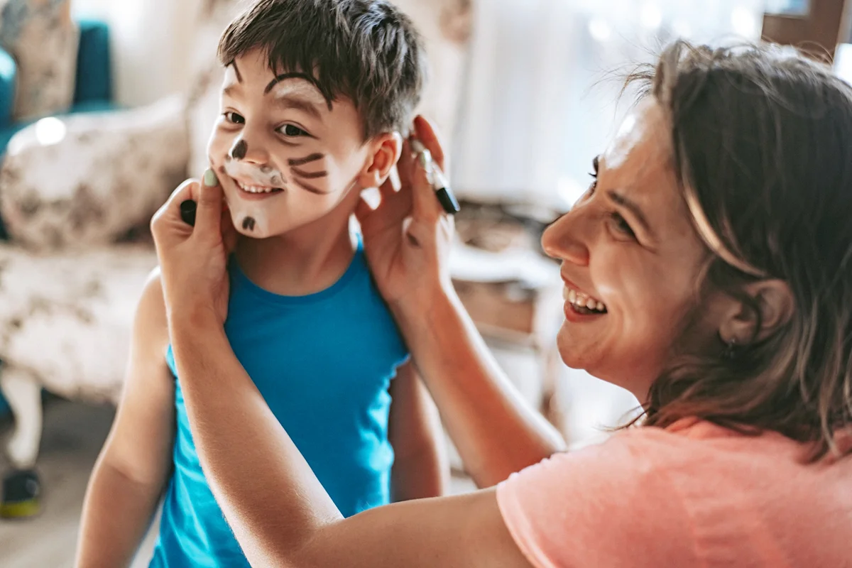Mom is doing face painting for her son