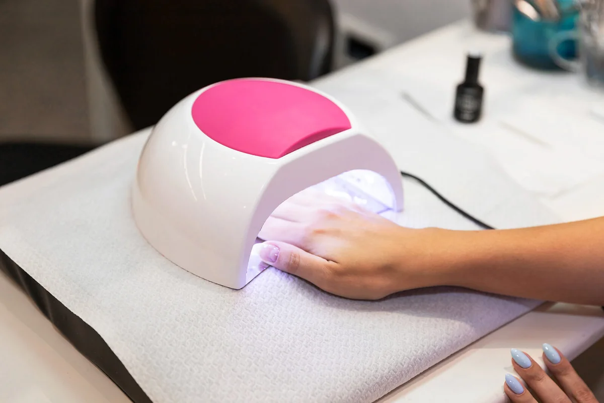 woman hands and lamp for nails on table