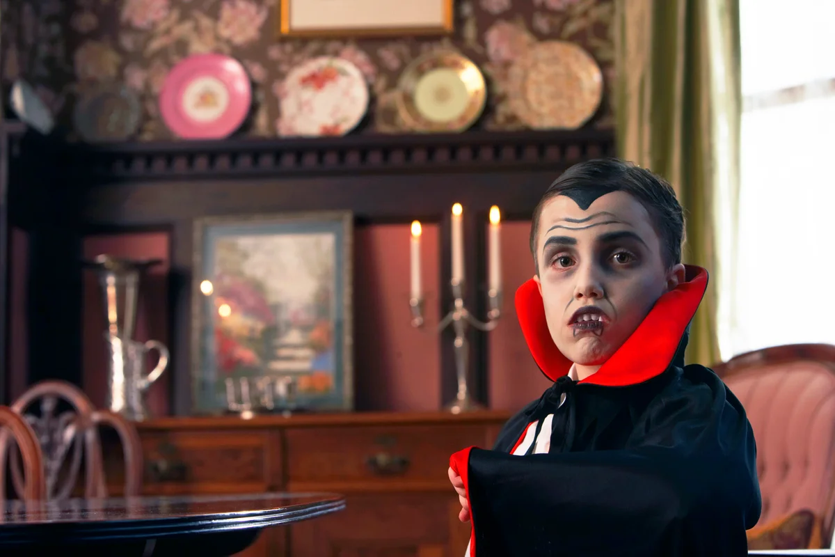 Boy dressed as vampire posing in living room