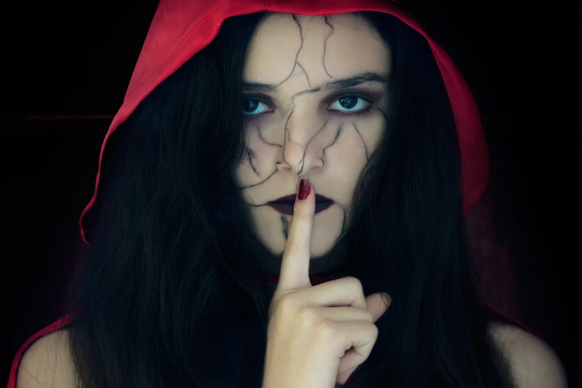 Girl with finger on lips and a painted face for Halloween