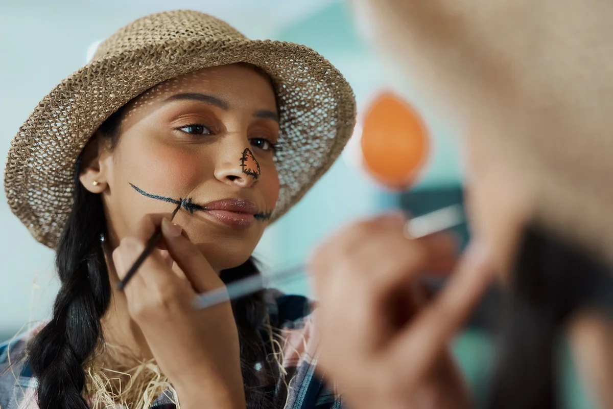 young woman applying scarecrow halloween makeup at home
