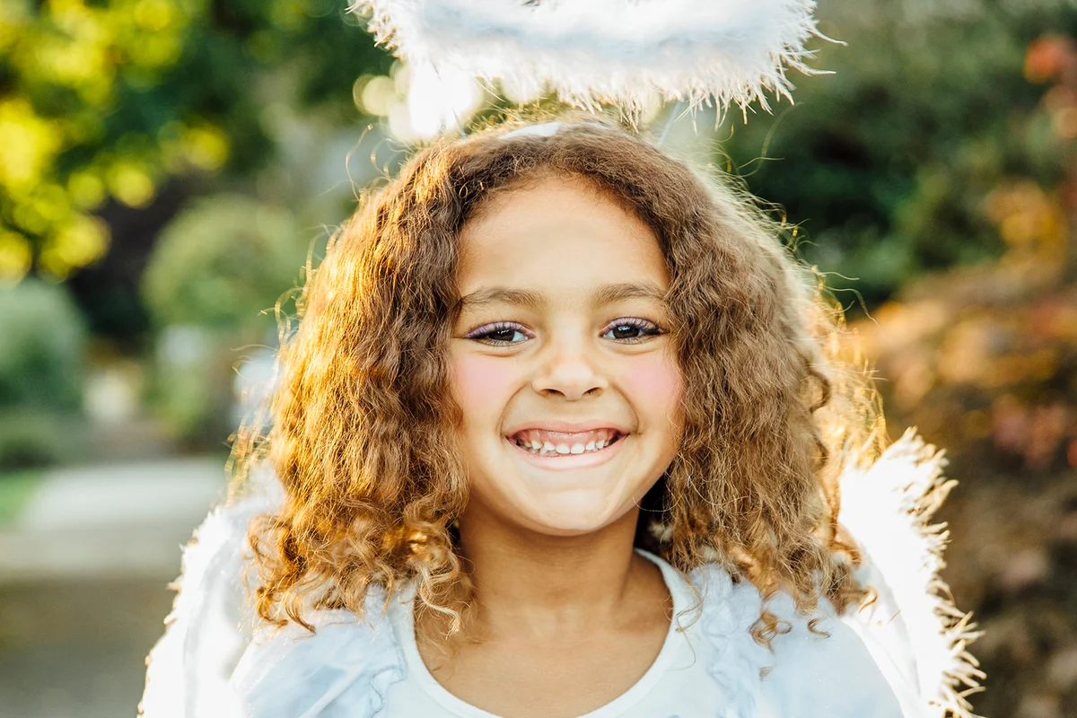 girl wearing angel costume and makeup on sidewalk
