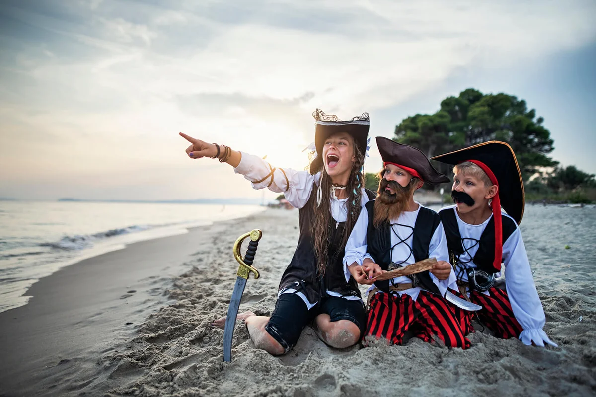 Kids pirates looking at treasure map on a beach