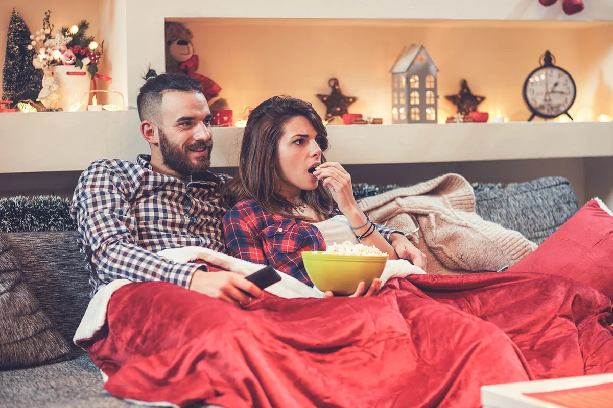 Couple at home eating pop corns while watching movie on tv