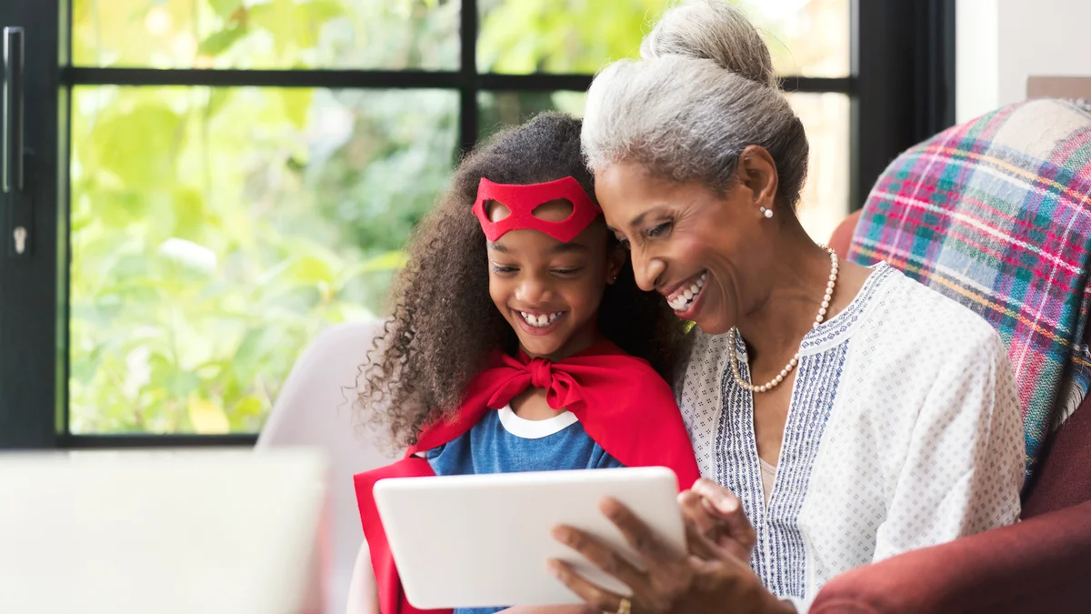 Smiling grandmother and granddaughter using tablet