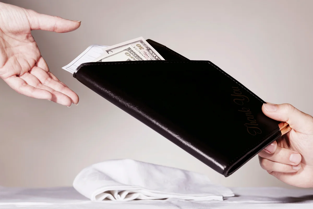 Person paying restaurant bill and leaving a tip