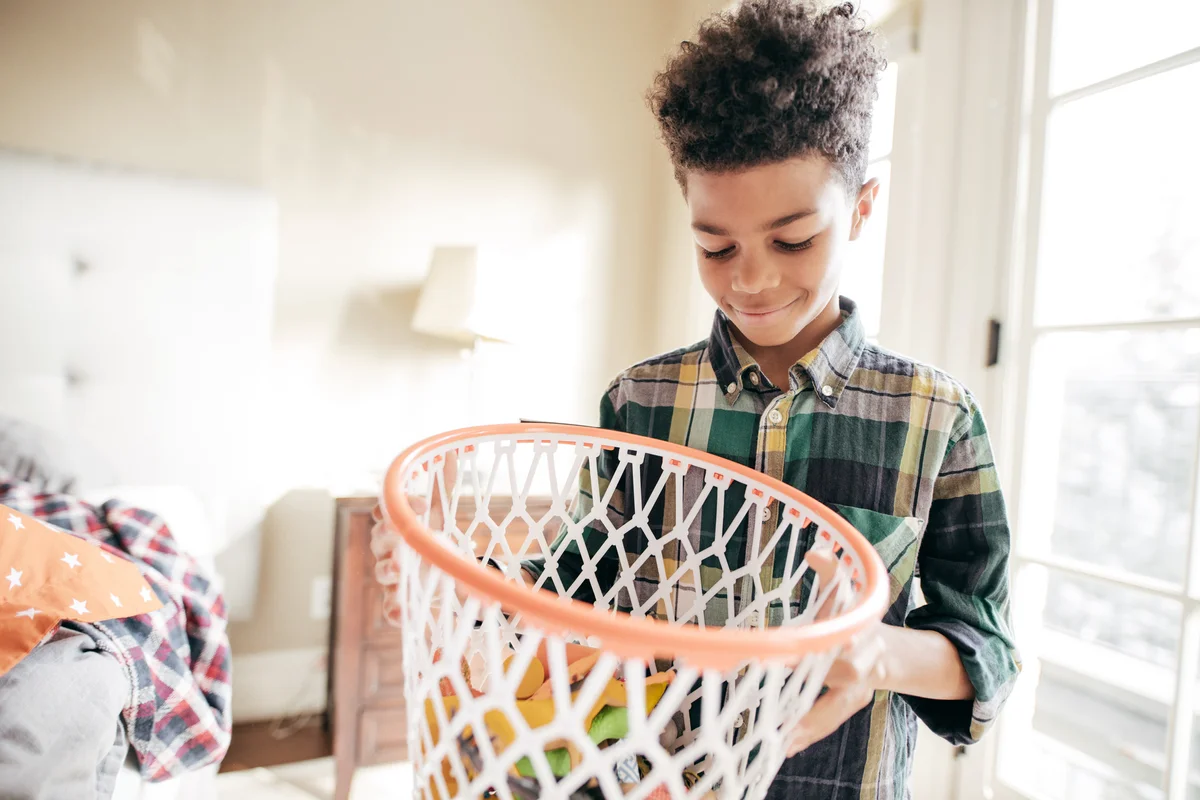 Boy with basket for toys cleaning his room