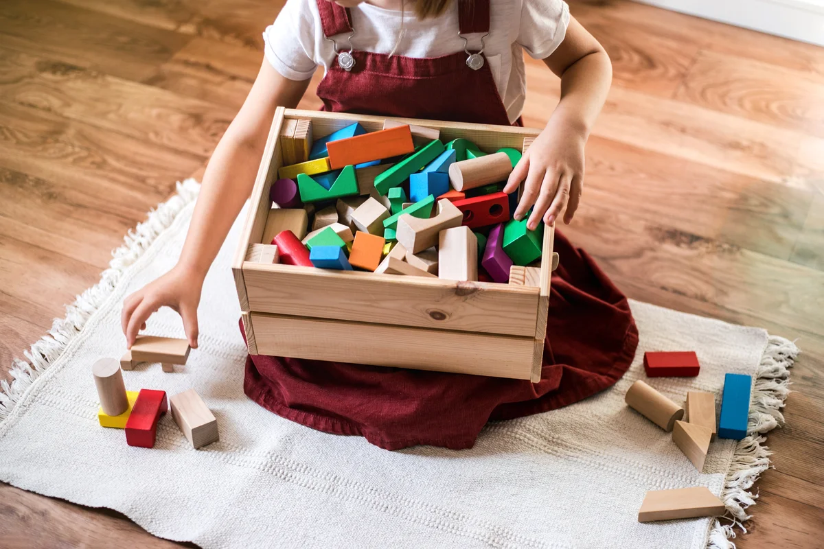 Little girl cleaning up the toy box at home