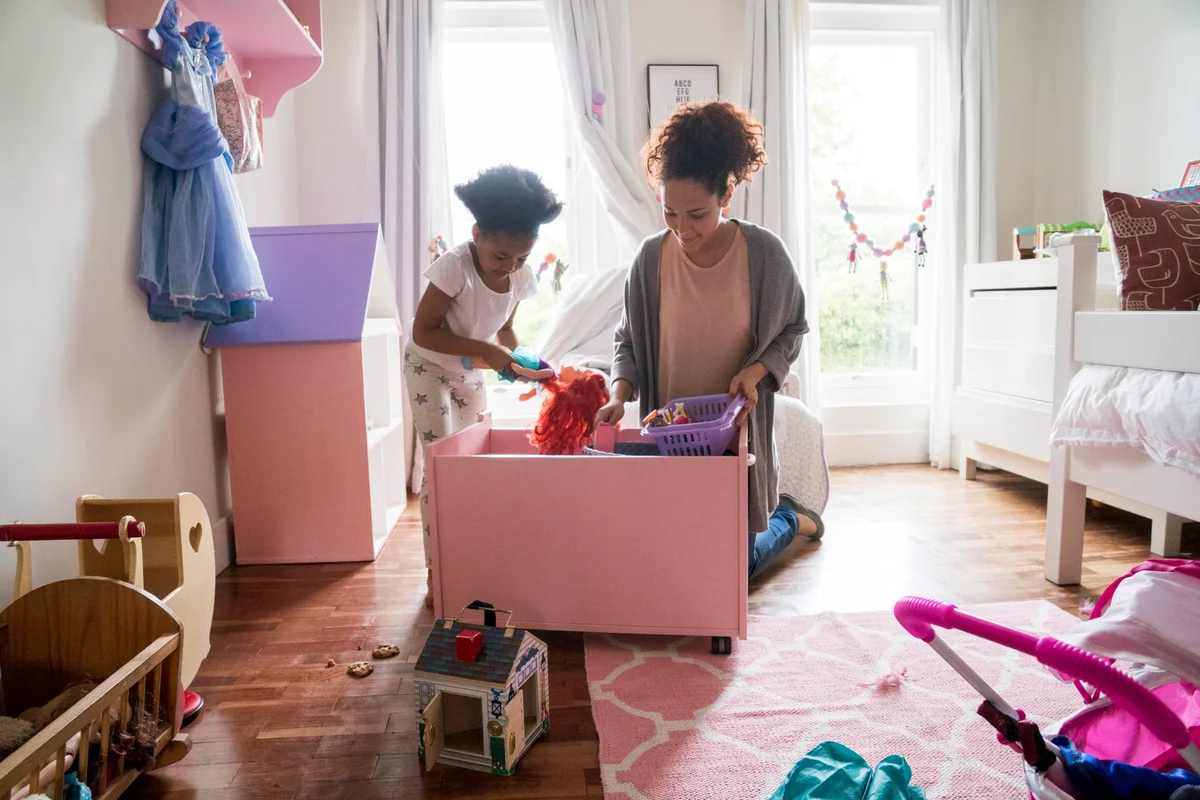 Mother and daughter picking up toys from container
