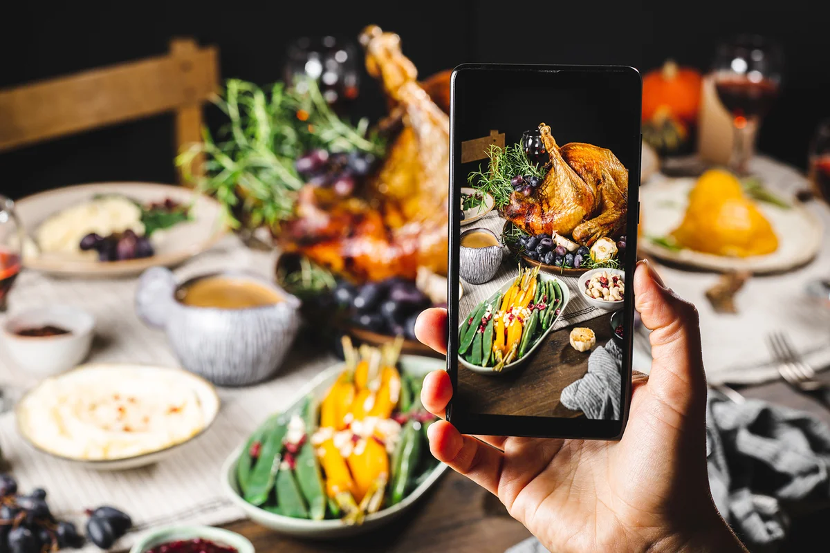 Hand taking photos of thanksgiving dinner with a smartphone