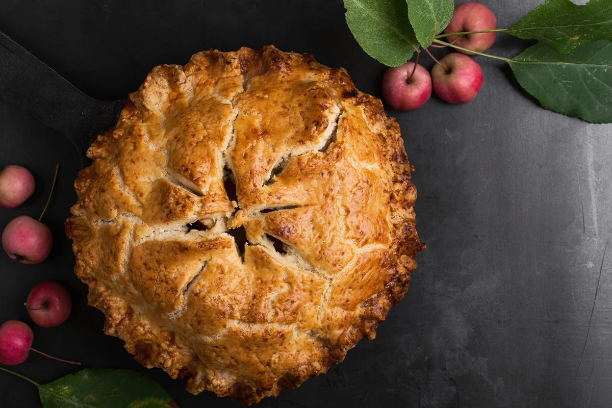 Apple pie in cast iron skillet on rustic table