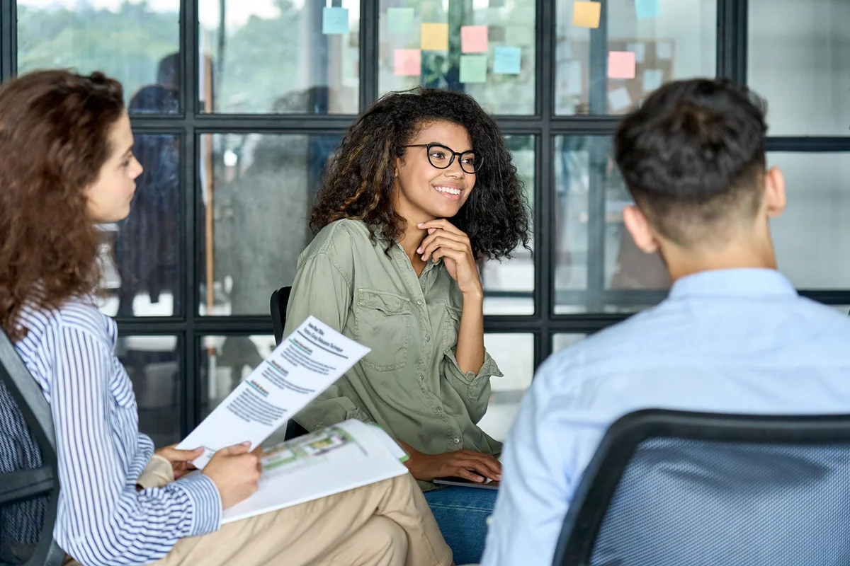 Happy colleagues listening to mentor leader in modern office