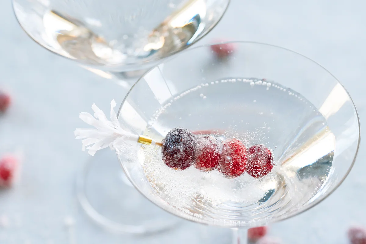 Festive red cranberries garnish a martini glass with sparkling bubbles