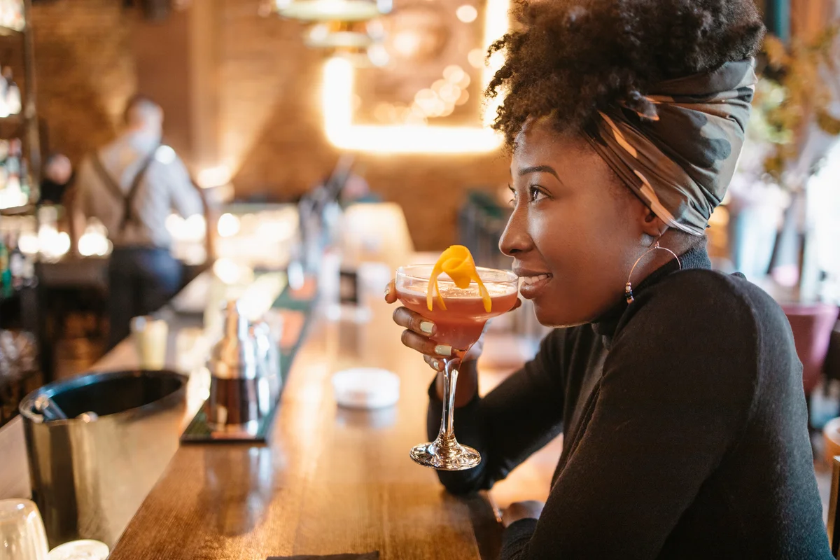 Young woman having a cosmopolitan while sitting at the bar