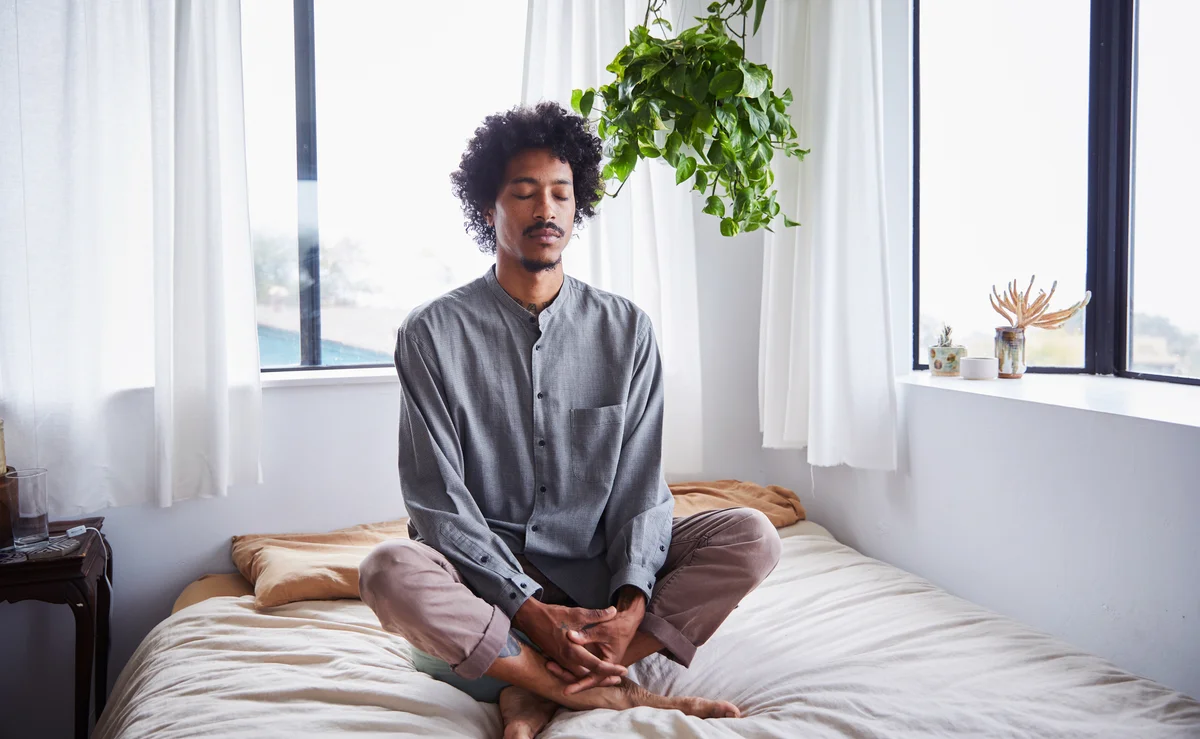 Young man meditating alone in his bedroom at home