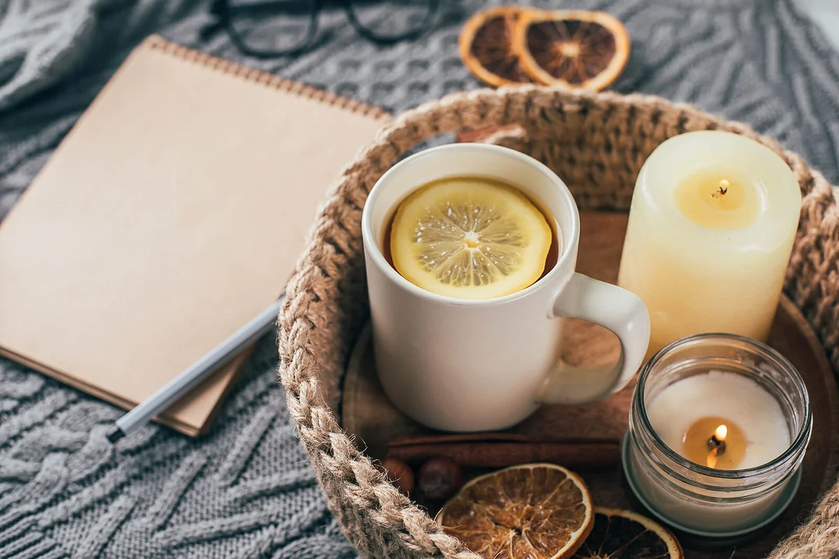 Cup of tea with lemon in jute knitted baskets, candles, dry orange
