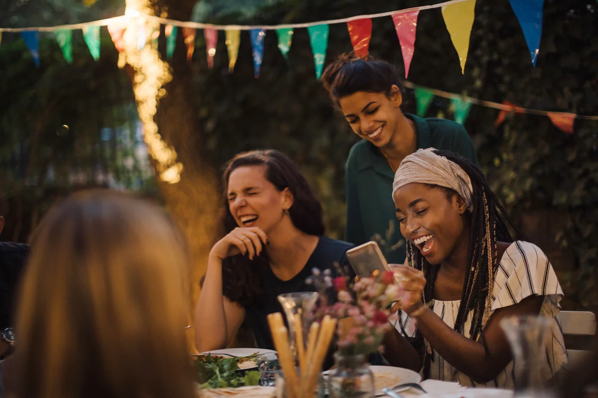 friends enjoying at table during dinner party in backyard
