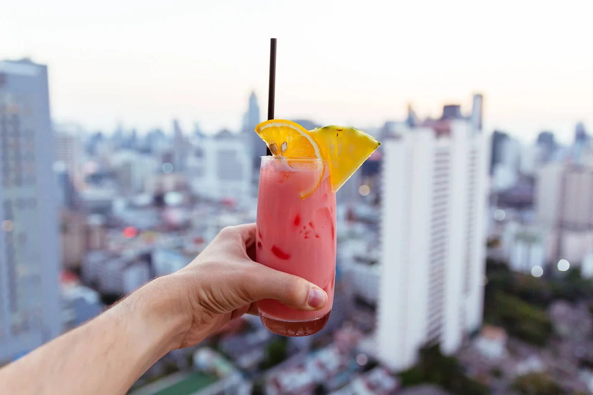 Drinking cocktail at the rooftop bar with city view