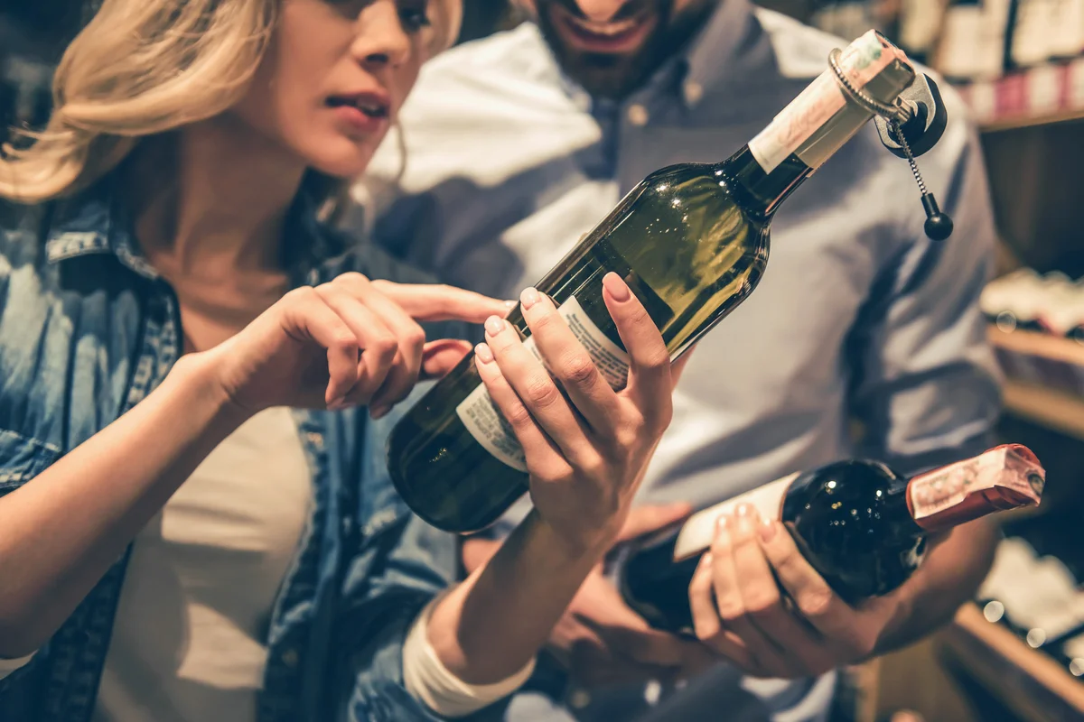 Young couple is talking and smiling while choosing wine