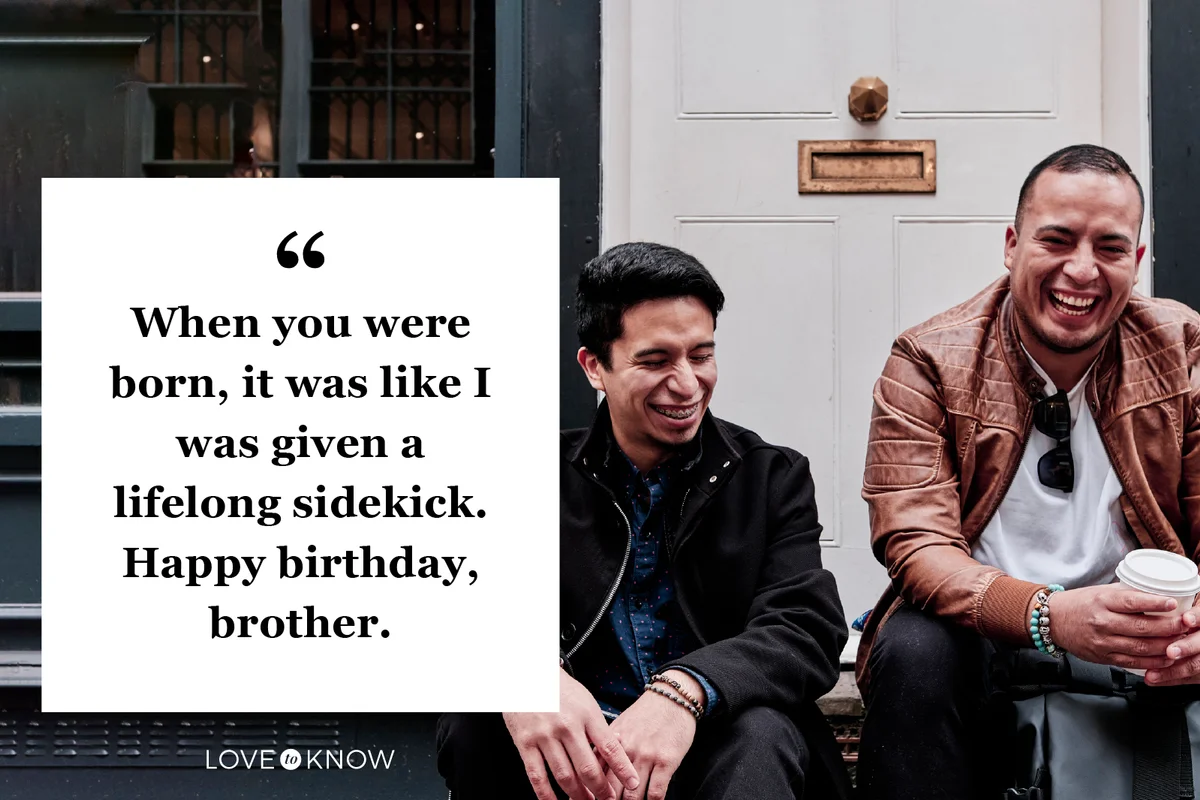 Two young men sitting on the steps of a door on the street while laughing