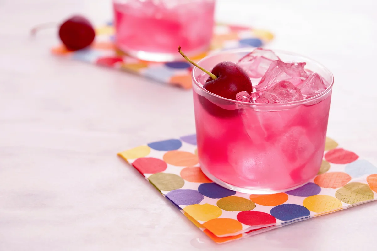 Red mocktail with cherry on colorful napkin