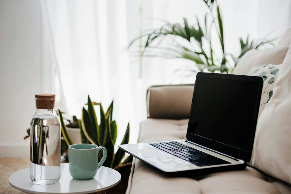 Laptop by cushions on couch at home