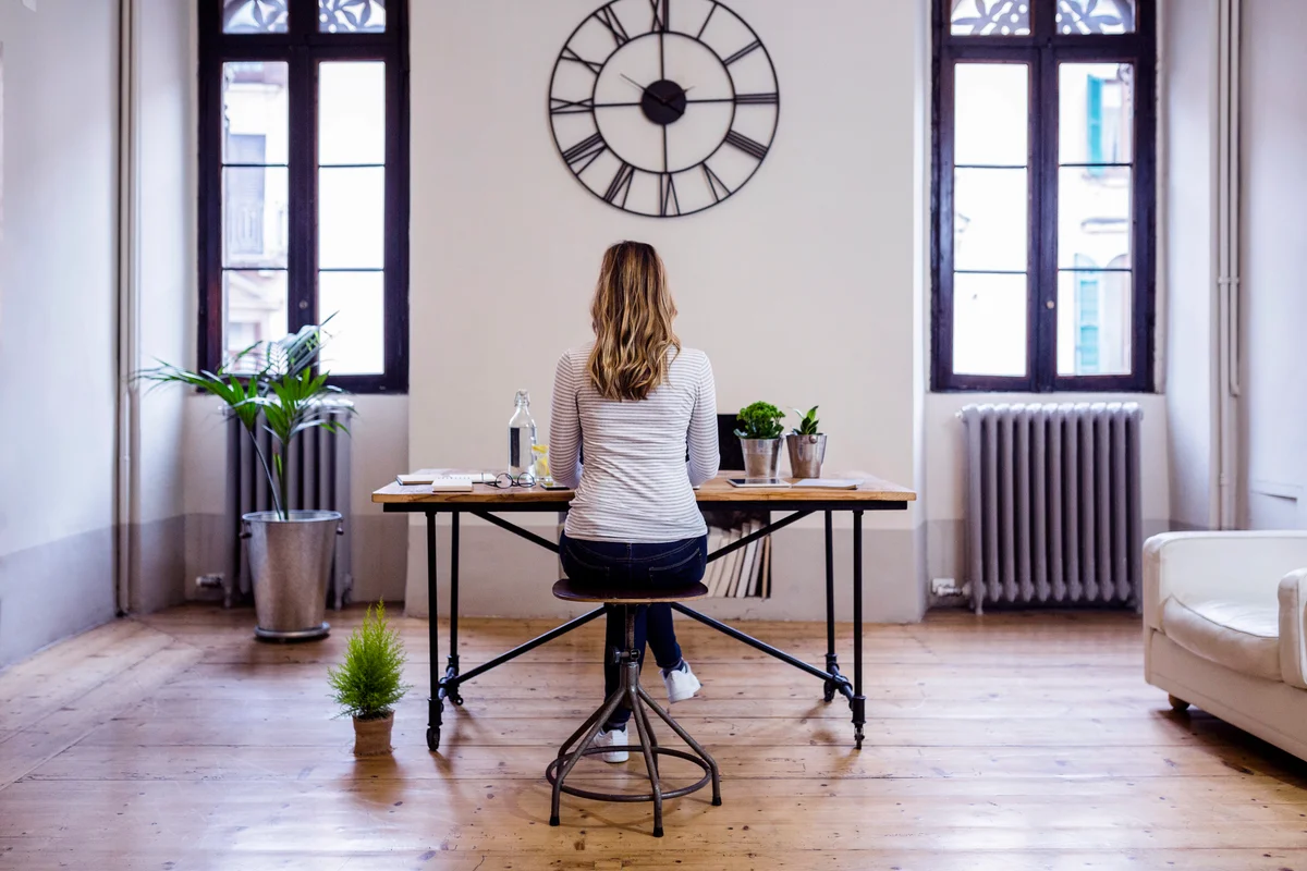 Rear view of woman sitting at desk at home